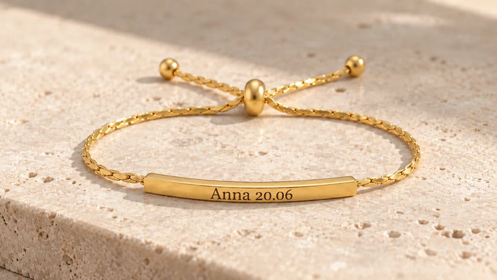 Goldenes Armband mit persönlicher Lasergravur auf hellem Stein