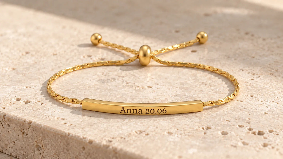 Goldenes Armband mit persönlicher Lasergravur auf hellem Stein