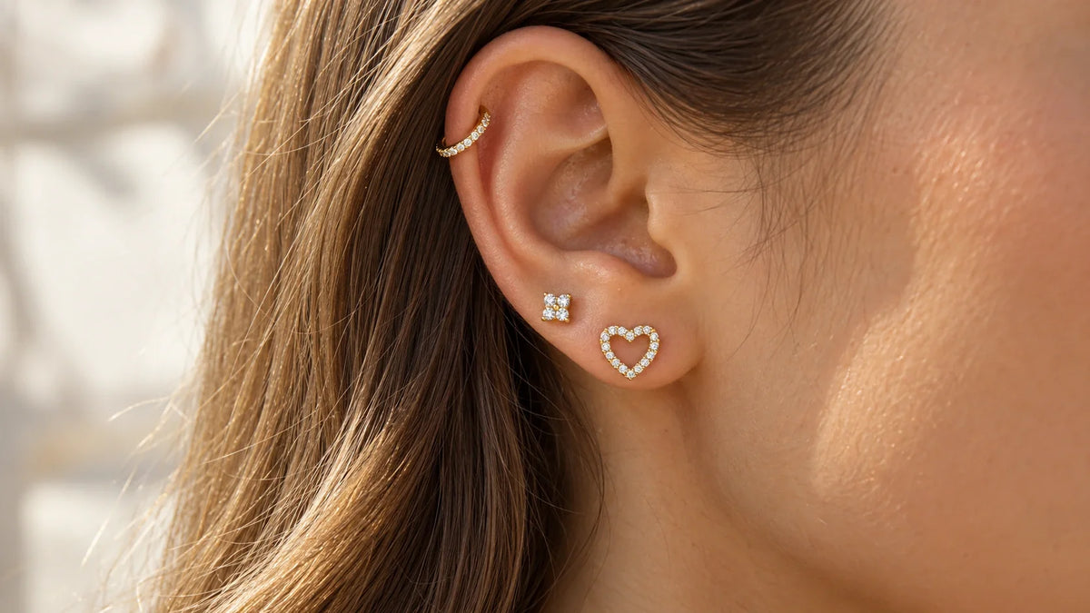 Goldene Piercings mit Steinen am Ohr an Helix und Ohrläppchen