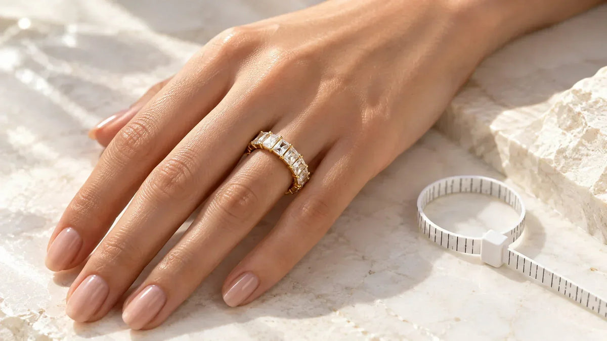 Goldener Ring mit eckigen Steinen an der Hand neben einem Ringmaßband zum Ringgröße messen