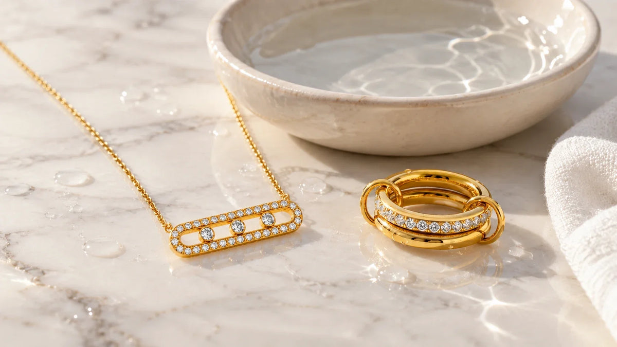 Goldene Kette und Ring mit Steinen nach dem Reinigen neben einer Schale mit Wasser