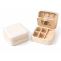 Kompakte Schmuck-Reisebox in Creme mit Reißverschluss, Spiegel und Fächern für Ringe, Ketten und Ohrringe.