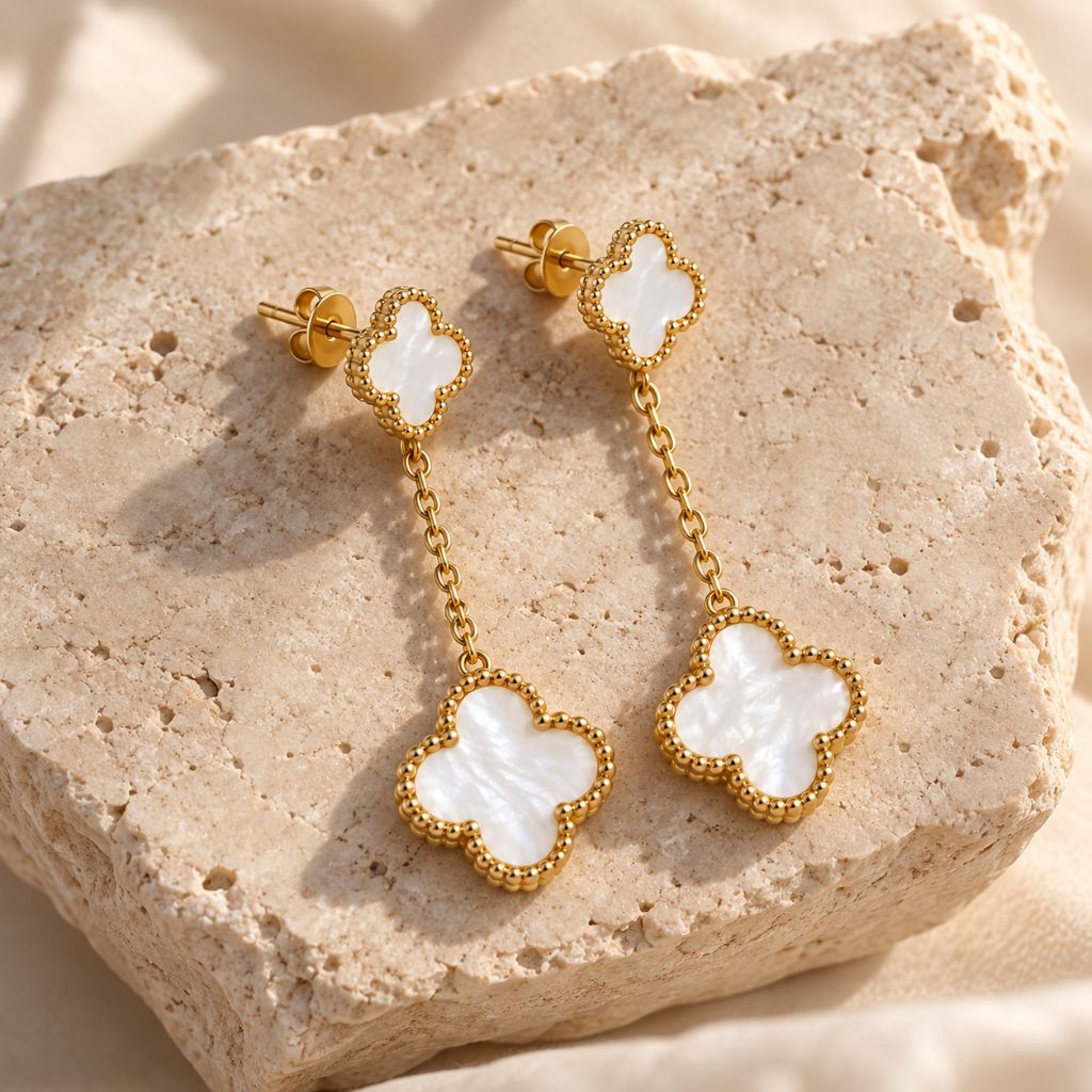 Weiße Kleeblatt-Ohrhänger mit Perlmutt in Gold auf hellem Naturstein, wasserfester Schmuck aus Edelstahl