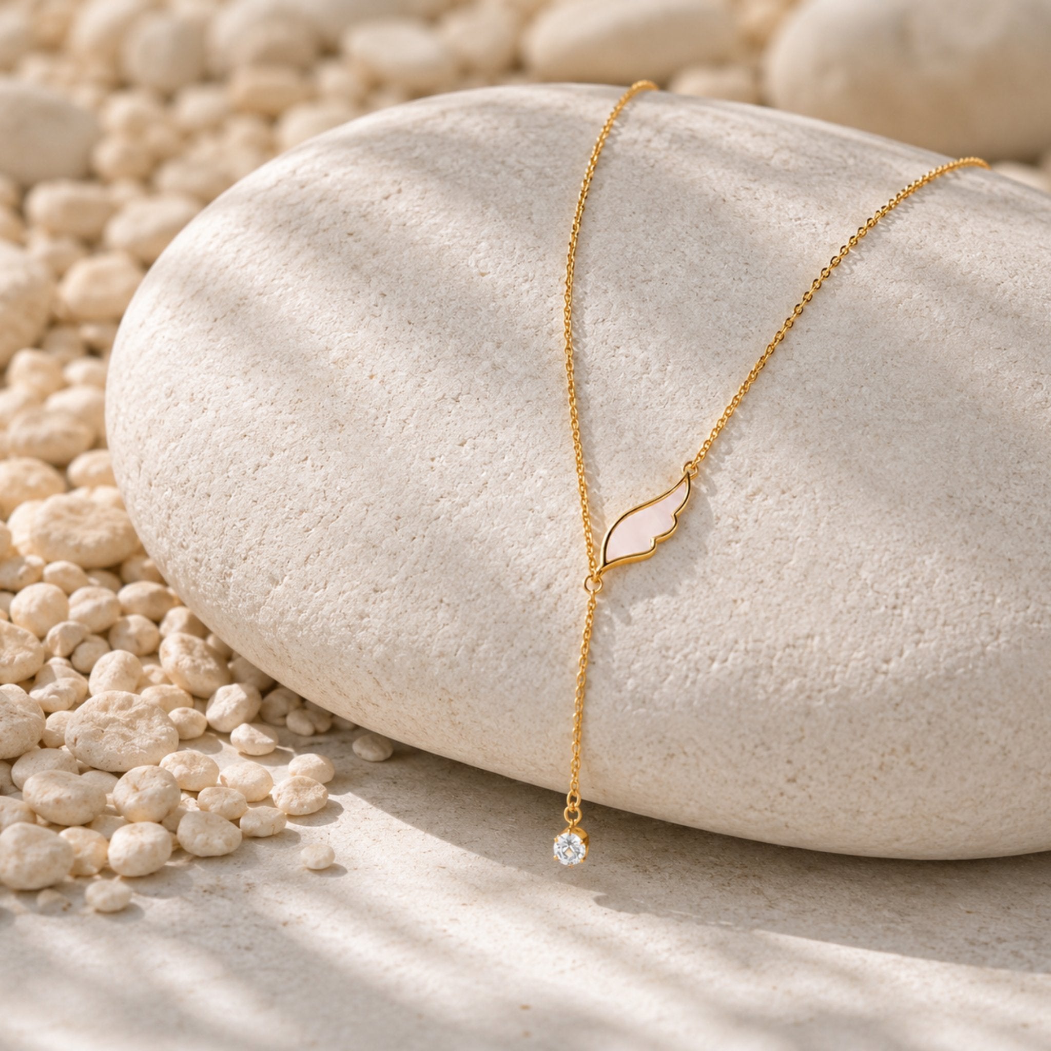 Goldene Angel Wing Kette mit Zirkonia Anhänger auf hellem Naturstein dekorativ präsentiert