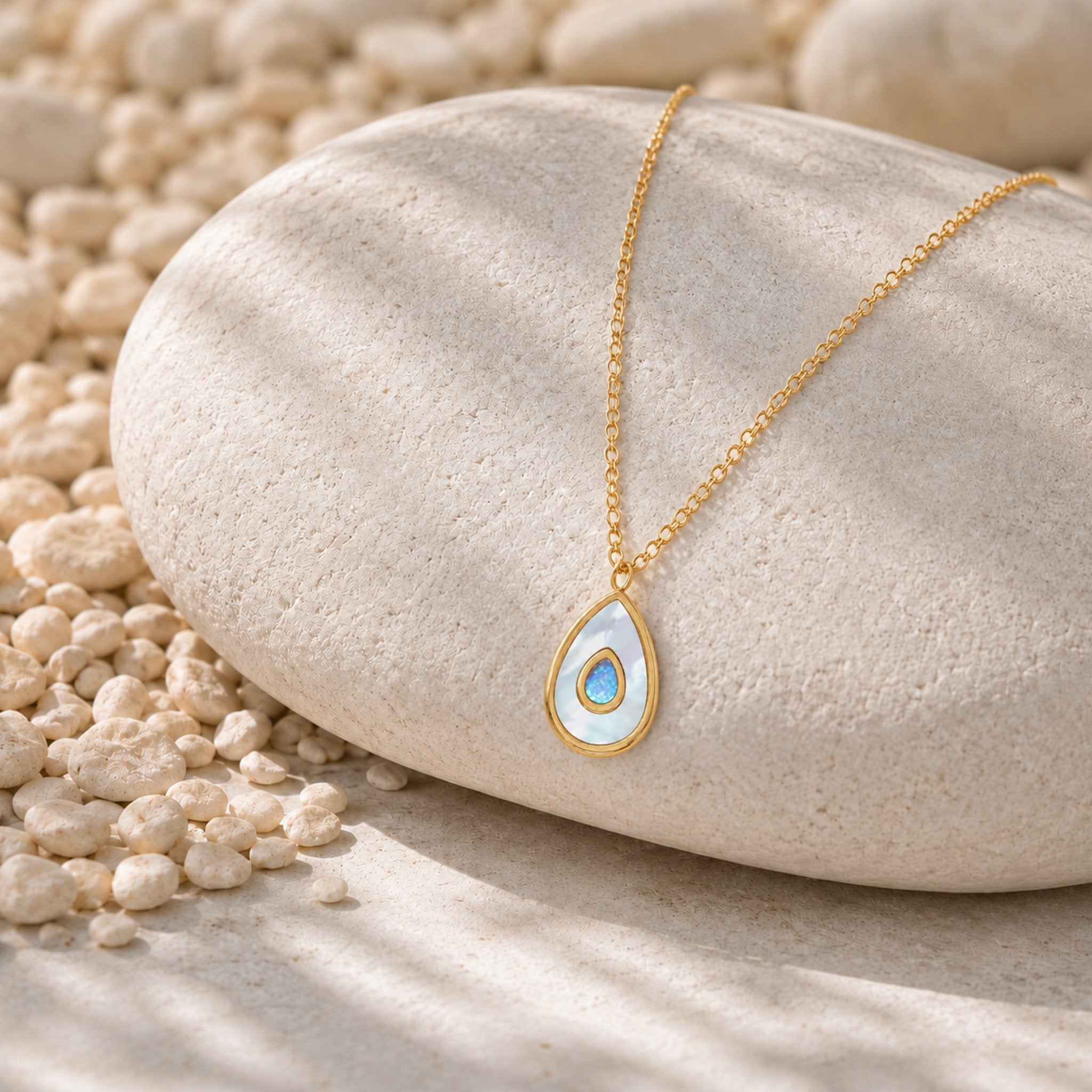 Goldene Blue Aura Drop Kette mit Opal Tropfen Anhänger auf hellem Naturstein dekorativ präsentiert