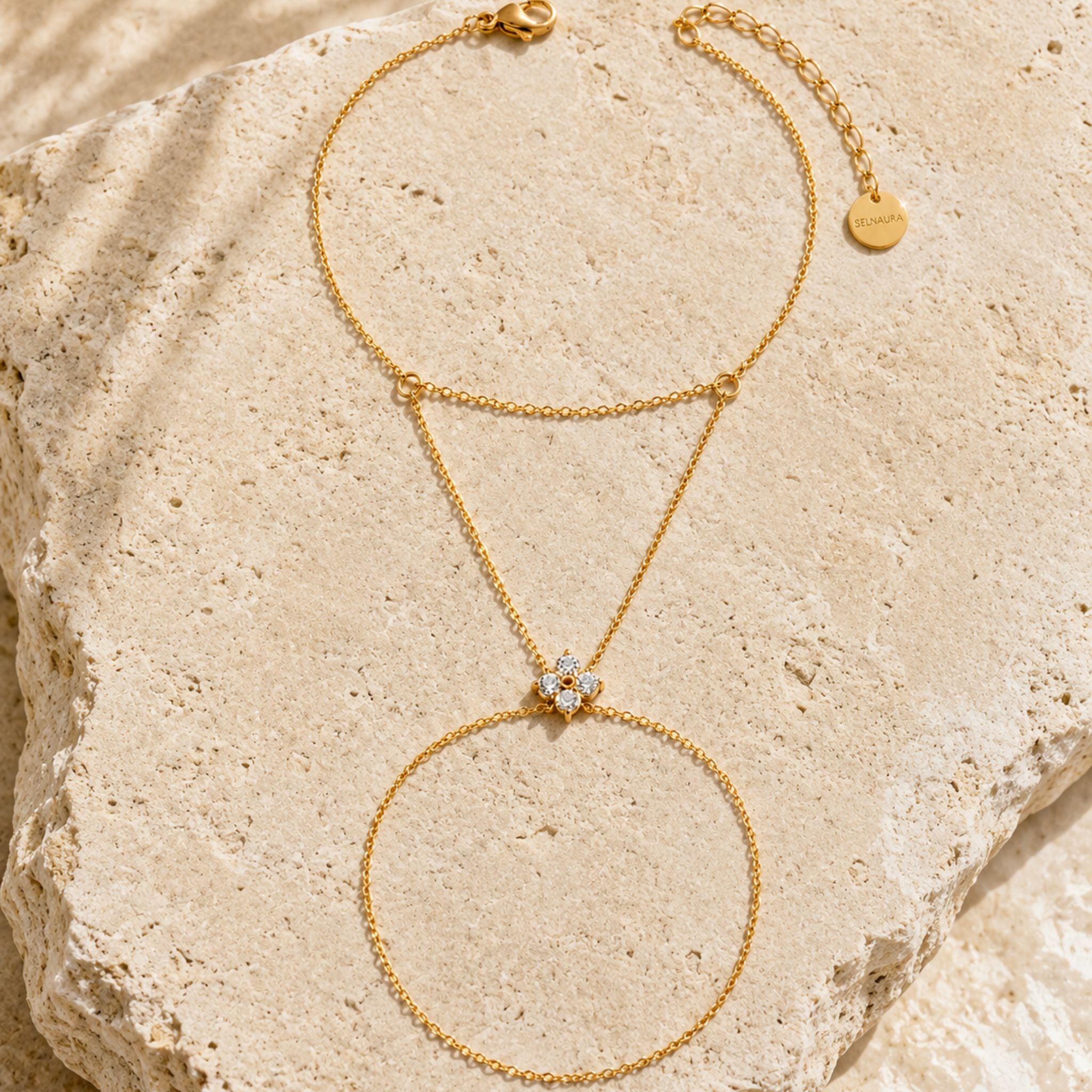 Flora Bloom Handkette in Gold mit floraler Zirkonia Blüte auf Naturstein gelegt