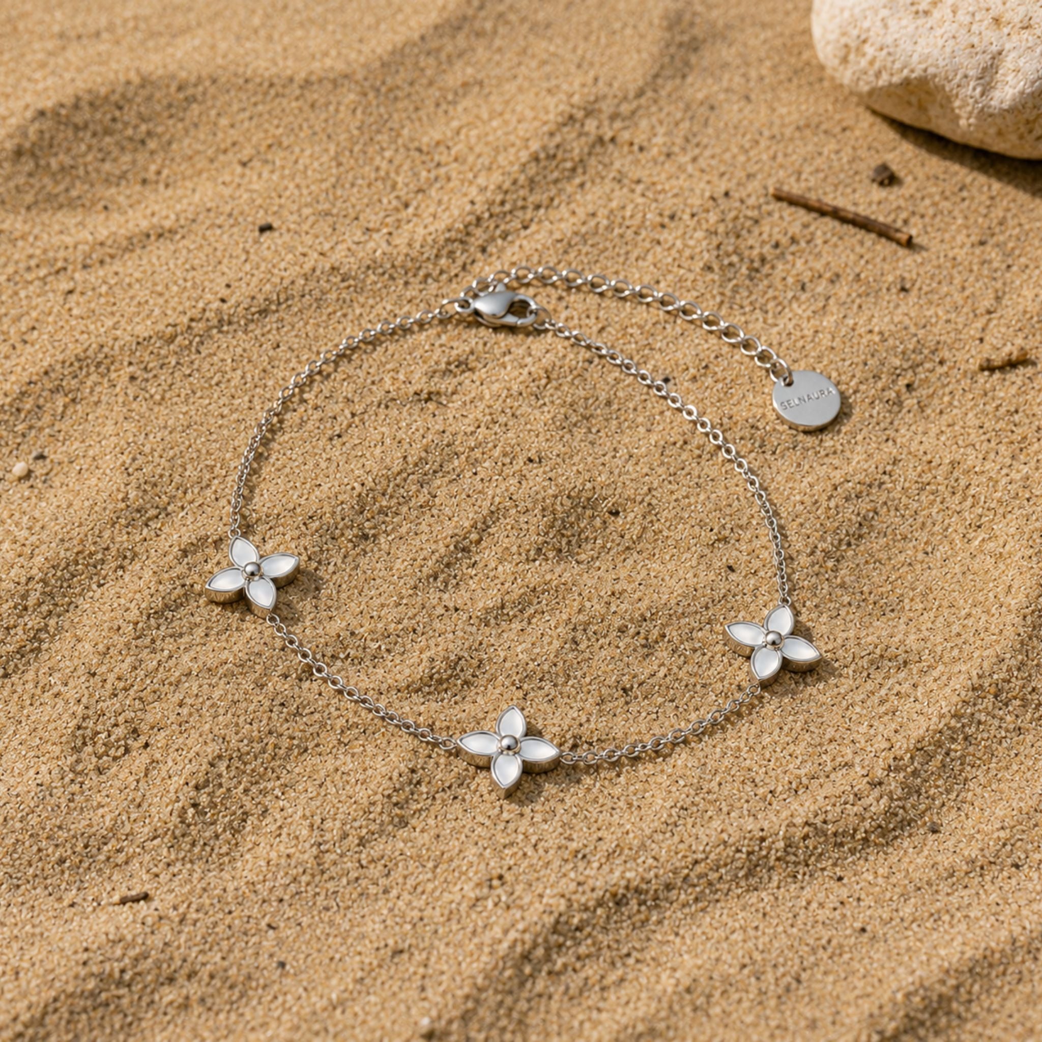 Flora Pearl Armband in Silber mit Perlmuttblüten auf Sand präsentiert