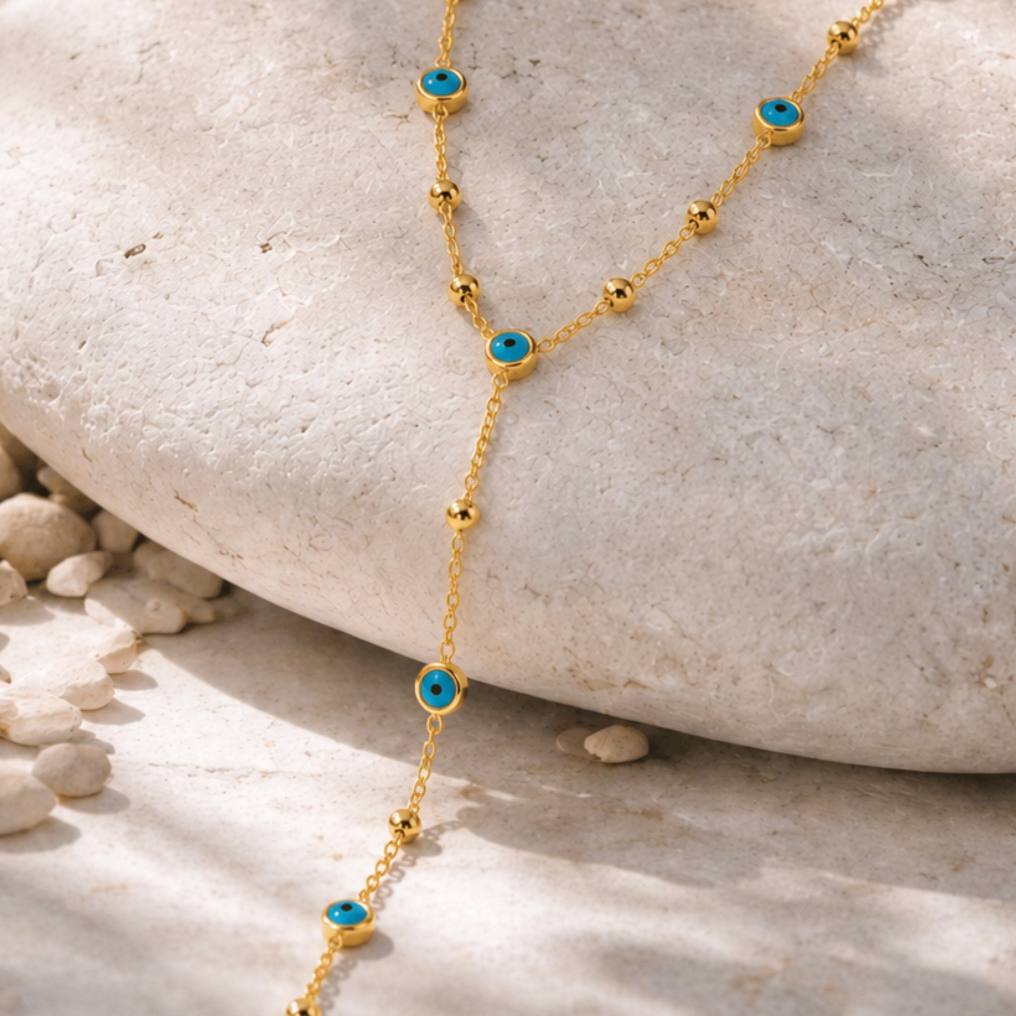 Golden Blue Nazar Kette mit blauen Nazar Augen und goldenen Perlen auf hellem Naturstein