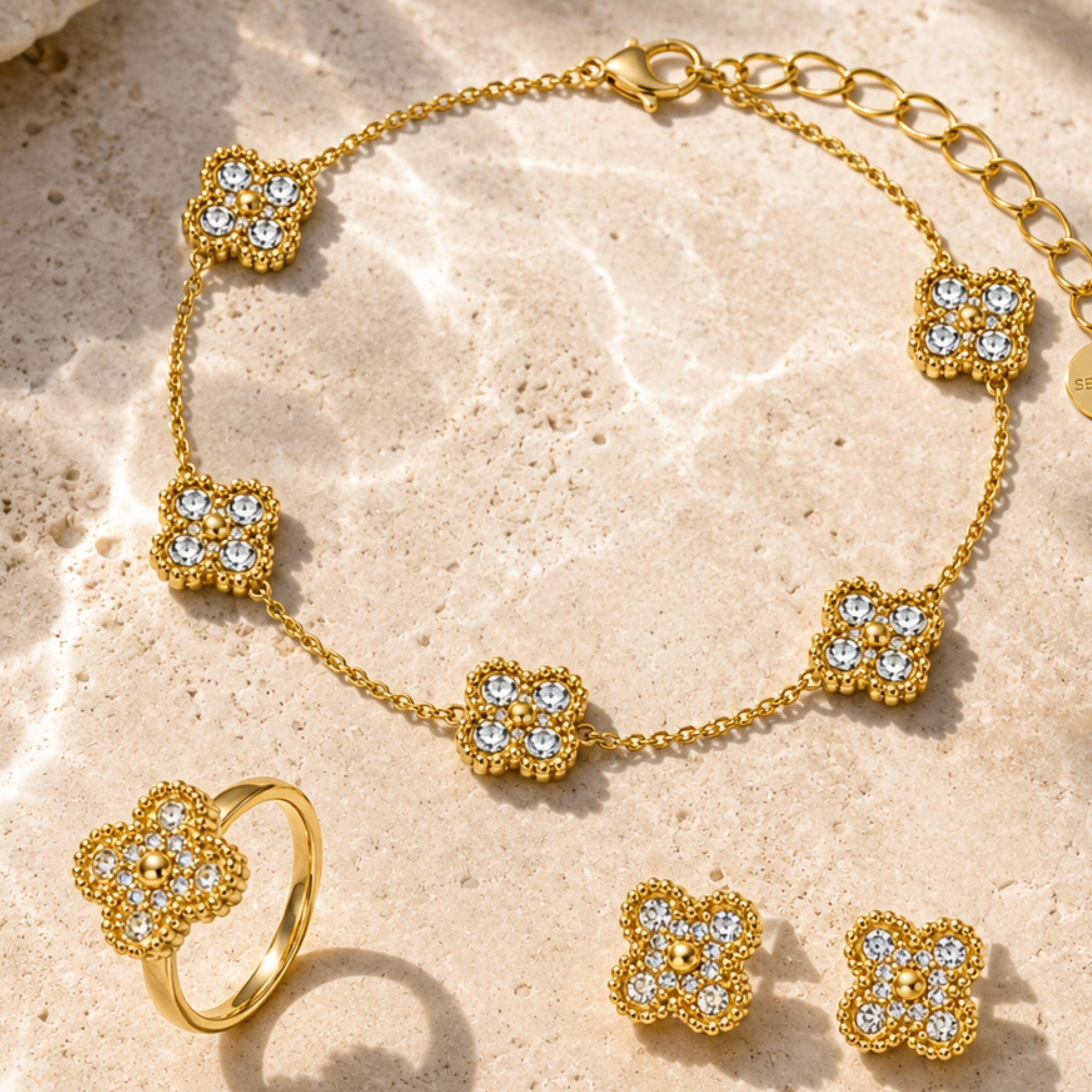 Golden Lumi Clover Set in Gold mit funkelnden Kleeblatt Schmuckstücken auf Naturstein
