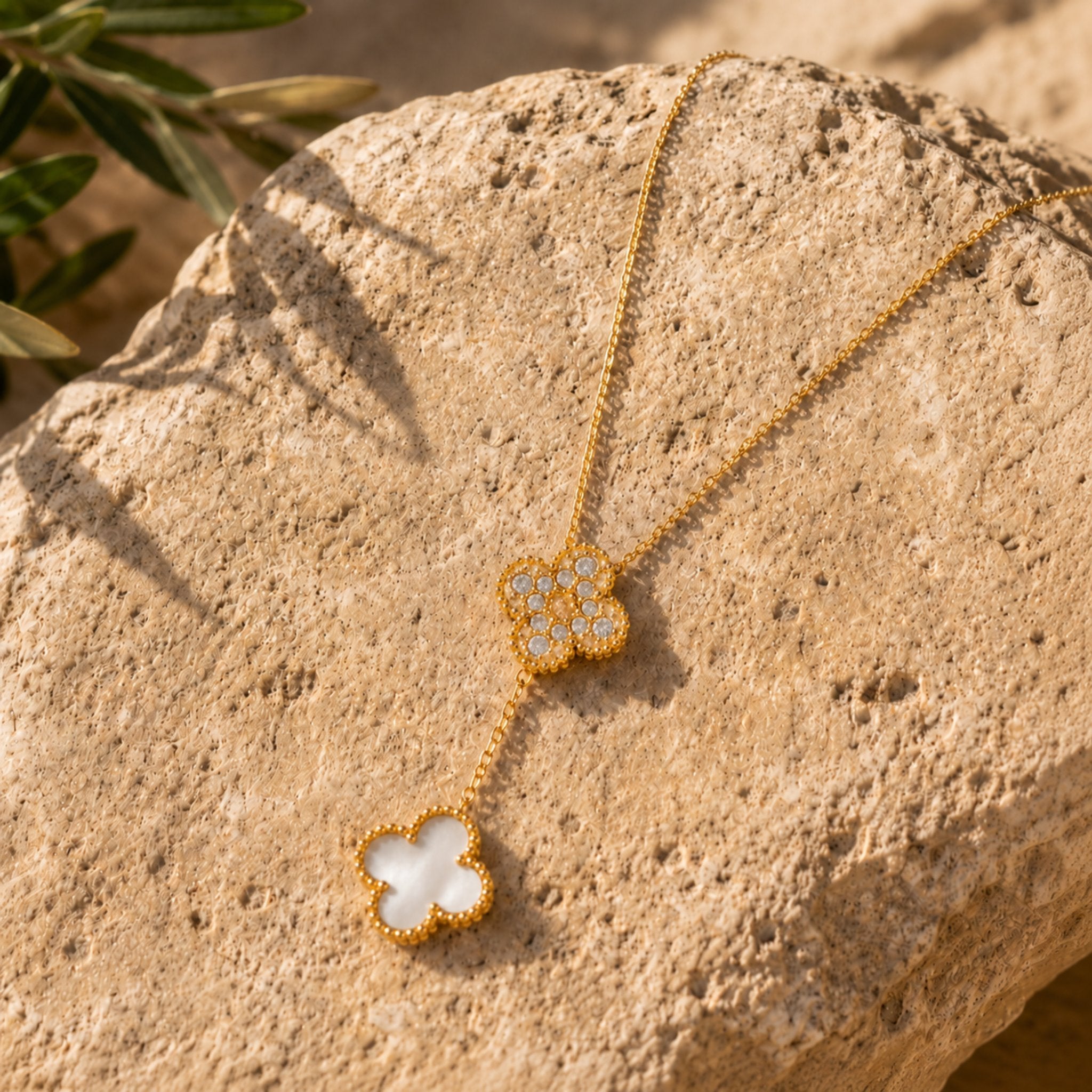 Goldene Moonlight Clover Kette mit weißem Kleeblatt auf Naturstein dekorativ präsentiert