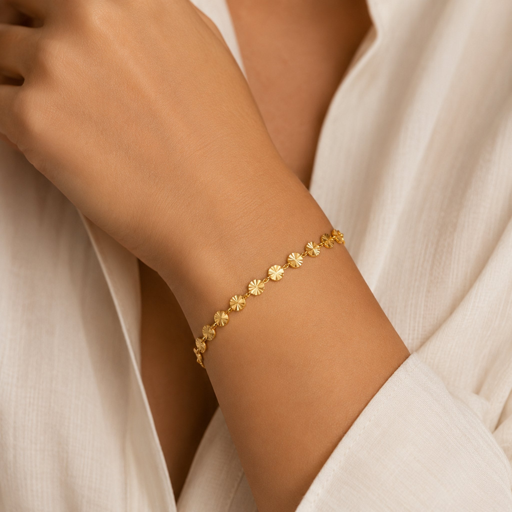 Dame trägt goldenes Soleil Armband mit glänzenden Sonnenplättchen